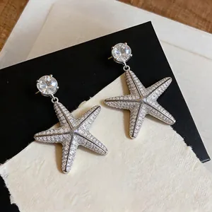 Primo piano squisito di orecchini pendenti a stella marina in zircone con ago in argento