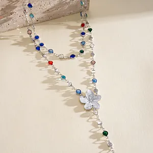 Close-up detail of a silver floral necklace with vibrant multi-colored gemstones
