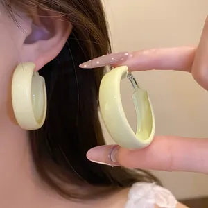 Detail showing pale yellow lacquer hoop earrings with a minimalist chunky design for women