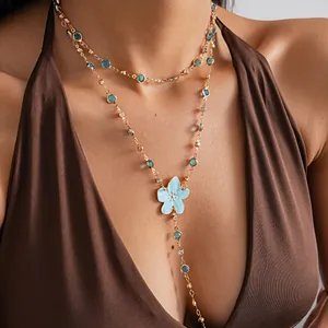 Detail view of a double-layered gold-tone necklace with blue stones and flower pendant.