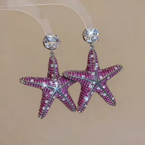 Dettaglio di orecchini a stella marina magenta con zirconi cubici pavé scintillanti.