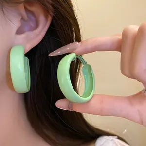 Detailed macro view of light green painted round hoop earrings with a smooth matte texture