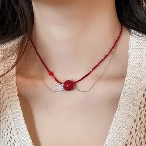Dettaglio di una collana di perle di cristallo rosso con ciondolo a fiore su una modella.