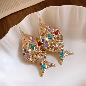 Detailed close-up view of gold fish-shaped earrings with colorful inset rhinestones
