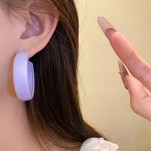 Detailed view of a glossy purple hoop earring worn on a model's ear with a silver needle