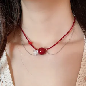 Dettaglio di una collana a due strati con perline di cristallo rosso e fiore trasparente