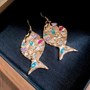 Detailed macro shot of gold fish-shaped earrings with colorful inlaid rhinestones