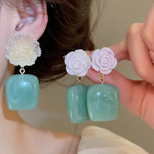 Close-up detail of resin ice flower earrings with translucent blue cube pendants in vintage style