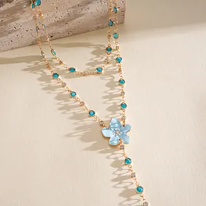 Macro view of blue resin flower and crystal charms on a layered gold-tone necklace
