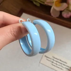 Close-up detail view of light blue spray-painted hoop earrings with a smooth glossy finish