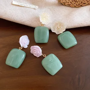 Detailed close-up of frost flower and rose resin drop earrings in vintage green finish.