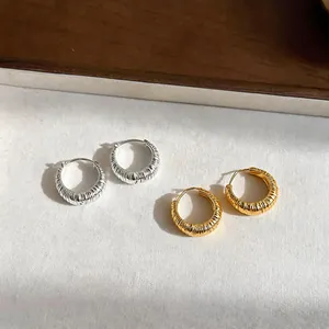 Dettaglio di orecchini a cerchio a forma di U testurizzati con finitura oro e argento