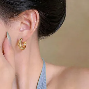 Elegante primo piano di orecchini a cerchio a forma di U dorati e testurizzati sul modello