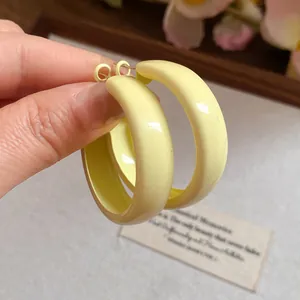 Detailed close-up view of minimalist pale yellow painted hoop earrings with silver needles