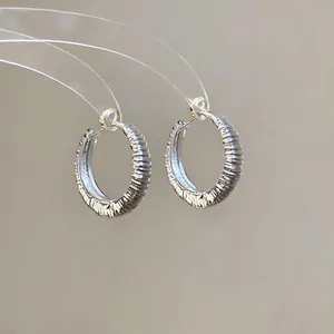 Vista ravvicinata di orecchini a cerchio in argento a forma di U con motivo a coste