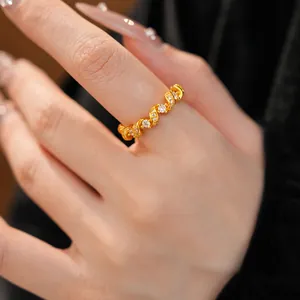 Détail en gros plan d'une bague dorée torsadée sertie de zircons brillants sur un doigt.