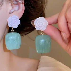Elegant detail showing the rose flower and green resin drop earrings in New Chinese style.