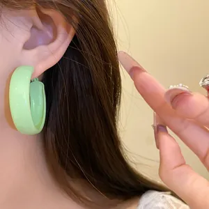 Close-up detail of a stylish mint green chunky hoop earring with a sleek matte finish