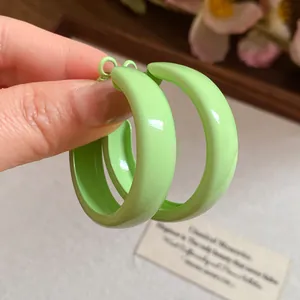 Macro view of light green spray-painted hoop earrings showing the glossy finish and silver needle