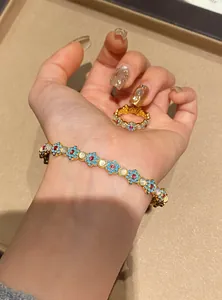 Detailed view of floral enamel bracelet with cat eye stones and red zircons on hand