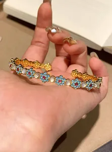 Detailed view of an open bangle featuring blue enamel flowers and cat's eye stones.