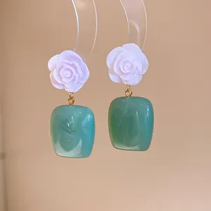 Close-up of pink resin rose and green square drop earrings in vintage style.