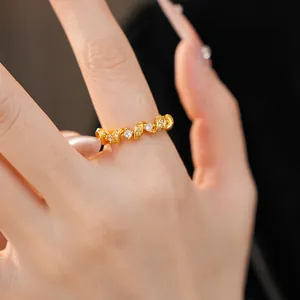 Gros plan détaillé d'une bague dorée torsadée sertie de pierres de zircone blanches.