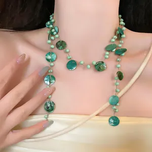 Vista dettagliata di una collana bohémien di perline di conchiglia verde sul collo della modella