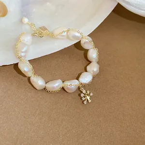 Close-up of elegant baroque freshwater pearl bracelet with gold chain and tree charm
