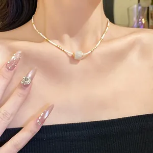 Elegante weiße Perlenkette mit Goldakzenten und einem durchscheinenden Steinanhänger