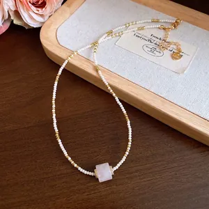 Vintage Perlenkette mit rosa quadratischem Steinanhänger auf einem eleganten Holztablett