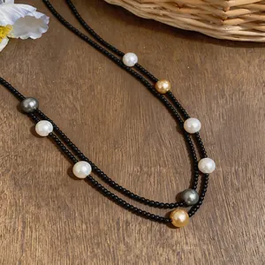 Detail view of double-layer necklace with black beads and multicolor pearls on wood
