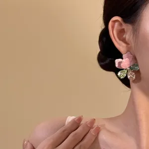 Detail view of oversized colorful rhinestone flower stud earrings on a model's ear