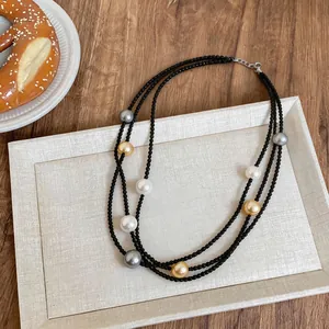 Detailed close-up view of a triple-layered black bead necklace with colored pearls