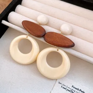 Close-up detail of retro resin and wood round pendant earrings in a jewelry box