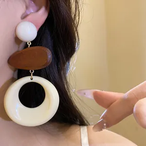Detailed shot of three-tier resin and wood geometric drop earrings on a model's ear