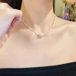 Detailansicht einer eleganten Perlenkette mit einem rosa Edelsteinanhänger an einem Model