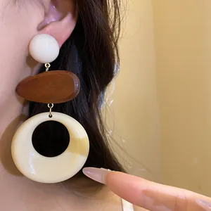 Macro detail of retro resin and wood geometric drop earrings on a model's ear
