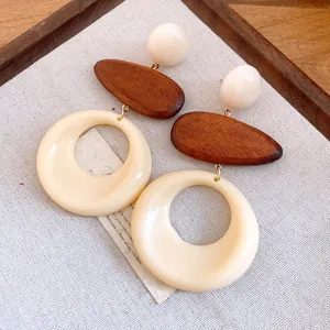 Macro detail of retro resin and wood round drop earrings on linen background