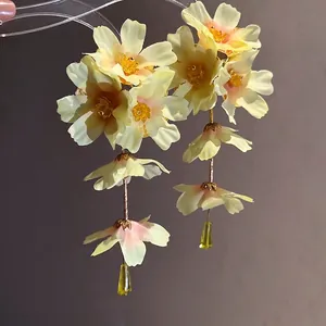 Boucles d'oreilles élégantes en tissu à fleurs jaunes avec pompons romantiques.