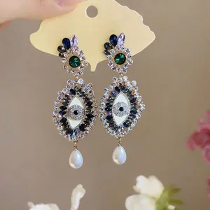 Vintage evil eye drop earrings with sparkling rhinestones and elegant white pearl drops.