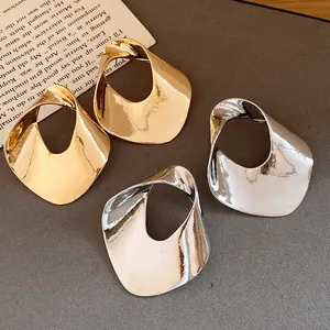 Dettaglio di orecchini geometrici cavi in stile minimalista oro e argento