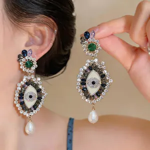 Detail of ornate vintage Evil Eye drop earrings with rhinestones and pearl on model