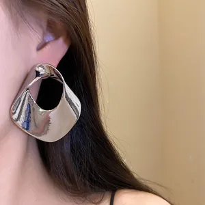 Grandi orecchini a perno in argento geometrici cavi indossati da modella asiatica