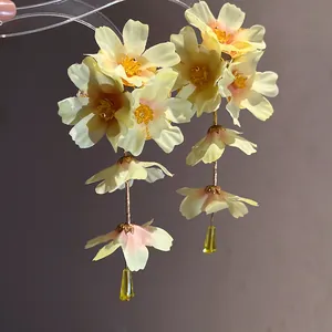 Détail de boucles d'oreilles en fleurs de tissu jaune avec un design de gland doux
