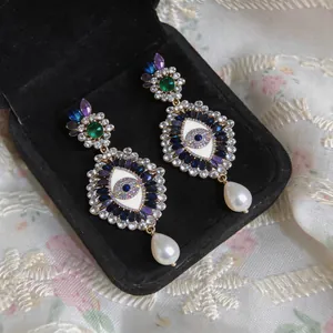 Detailed close-up of vintage Evil Eye drop earrings featuring crystals and pearls.