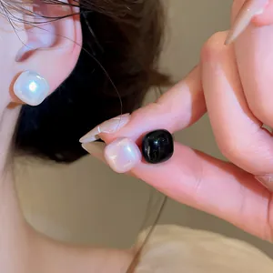 Close-up view of French vintage square pearl studs and black glossy square earrings for women.