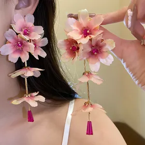 Vue rapprochée de boucles d'oreilles fleurs en tissu rose avec détails en strass.