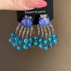 Detail view of vintage oval resin earrings with blue rhinestone tassels and silver needles
