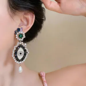 Close-up of ornate evil eye earring with colorful rhinestones and a teardrop pearl.